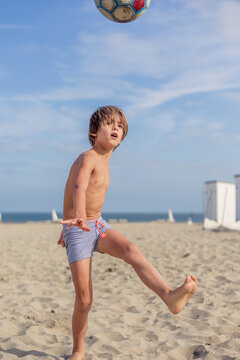 Young Boy Playing Football Barefoot on a Sunny Beach