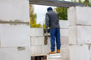 Fototapeta premium A man in a blue jacket and blue pants is working on a wall