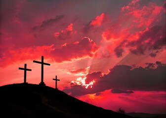 Three crosses rise solemnly on a rugged hill, their dark silhouettes outlined by the fiery glow of a setting sun. The sky is filled with dramatic clouds, bathed in shades of amber and crimson, casting
