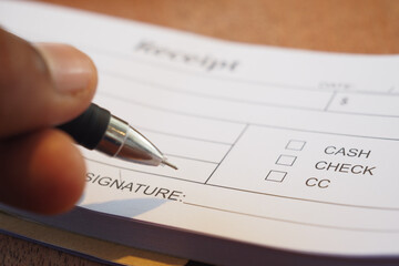 Signing the Receipt by Hand Using a Pen on the Payment Form Provided