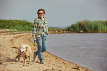 A beautiful woman walks with a dog near the sea in Denmark