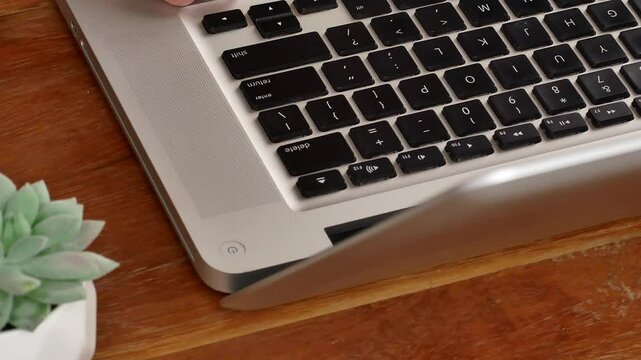 The computer user's finger, he presses the delete key on the computer keyboard. Asian working man is pressing the "delete" button on the laptop keyboard.