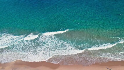 Aerial drone overview of gentle ocean waves rolling onto sandy shores at West Palm Beach, Florida, glistening ripples on clear water