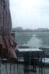 View of the raging sea through the window of the cafe. The waves are hitting the rocks. Autumn, rain, cloudy weather. Vertical video.