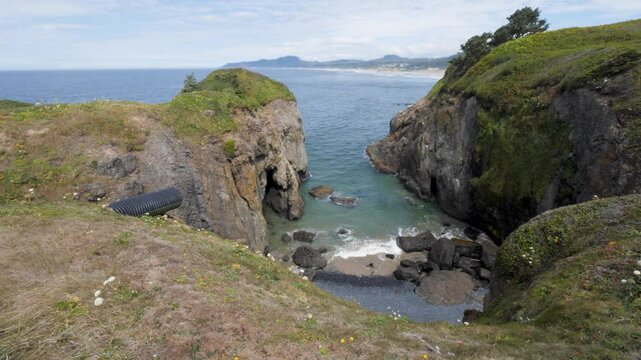 Ocean Bay Inlet, Secluded Mini Beach Below Cliffs. Yaquina Head, West Coast, Newport Oregon, USA. Looking North Towards Otter Rock. Corrugated Plastic Drainage Pipe Sits Above the Water.