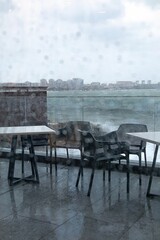 View of the raging sea through the window of the cafe. The waves are hitting the rocks. Autumn, rain, cloudy weather. Vertical video.