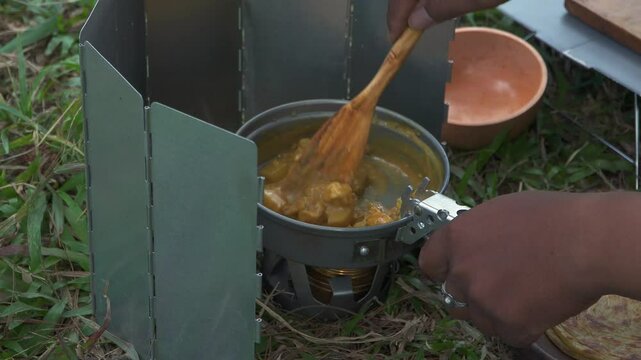 The concept of Bushcraft camping alone in a pine forest area while cooking curry with roti canai. An Asian male adventurer is solo camping while preparing and cooking in beautiful nature