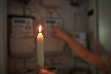Checking the electricity power meter with a candle in cold winte