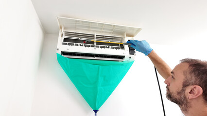 Man cleaning and maintaining air condition unit at Man cleaning and maintaining air condition unit...