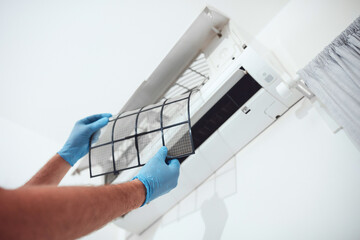 Man cleaning  filters and maintaining air condition unit at home
