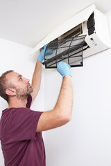 Man cleaning and maintaining air condition unit at home.