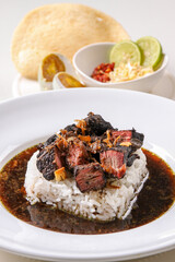 A bowl of Indonesian traditional dish Rawon featuring tender beef, a rich black broth, and served with steamed rice, salty boiled egg, shrimp crackers and a side of sambal in isolated white background