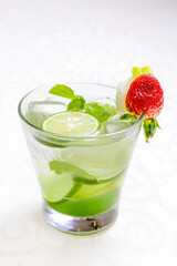  A glass of sparkling lime and mint cocktail garnished with a fresh strawberry in isolated white background