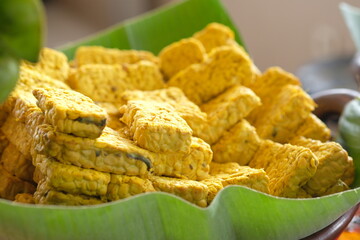 Tempe with yellow turmeric seasoning on banana leaf. Indonesian food. Tempe or tempeh is fermented soybean
