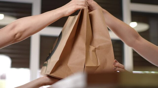 A friendly staff member warmly hands over a takeout order to a satisfied customer in a cozy cafe setting