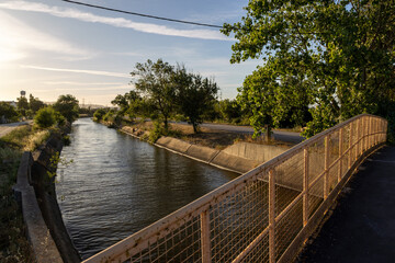Fototapeta premium Irrigation canal flowing under bridge at sunset in the countryside
