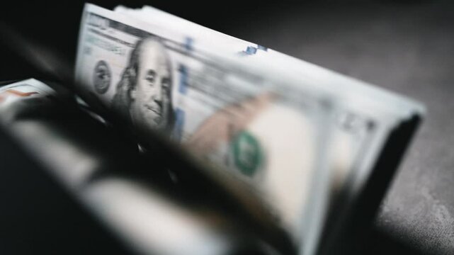 An automated money counting machine sorting $100 bills with Benjamin Franklin&rsquo;s image. Symbolizing financial savings, budgeting, and cash management.