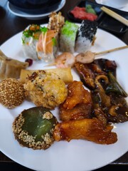 Delicious asian food buffet displaying variety of dishes including sushi, spring rolls and sesame balls all you can eat