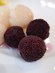 Red bayberry and lychees resting on white plate in prague all you can eat