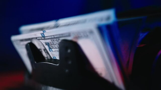 Close-up of a money counting machine with blue and red lights counting bills. Concept of finance, banking, corruption and bribery.