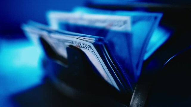 Close-up of a money counting machine with blue and red lights counting bills. Concept of finance, banking, corruption and bribery.