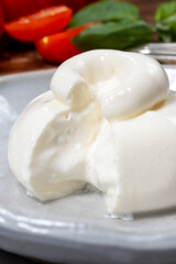 Cheese collection, eating of fresh soft white burrata cheese ball made from mozzarella and cream from Apulia, Italy, close up