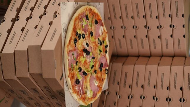 A delicious and tempting pizza beautifully placed amidst stacked delivery boxes, just perfect for food lovers