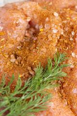 a salted piece of fresh chicken meat on paper sprinkled with spices