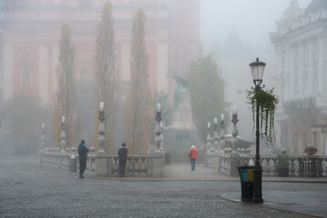 People walking on a foggy bridge in ljubljana city center