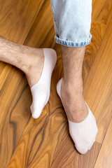 Man in stylish white short sock on light interior background, closeup.rear view, heel view