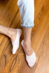 Man in stylish white short sock on light interior background, closeup.rear view, heel view