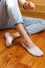Man in stylish white short sock on light interior background, closeup.rear view, heel view