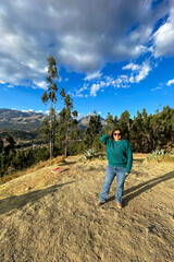 A woman in a green sweater stands in front of a mountain range