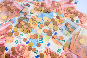 euro bills and coins lying on a white table.