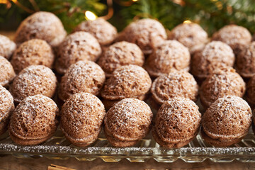 Nut shaped homemade Christmas cookies filled with cream and dusted with sugar, with fir tree branches in the background