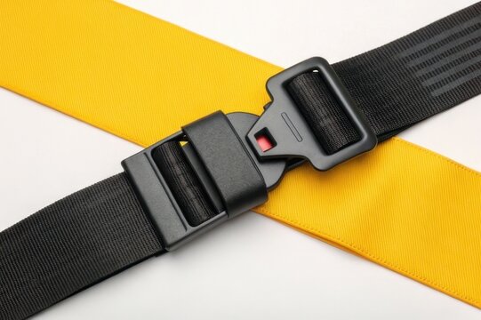A close-up of a car seatbelt buckle, featuring a black clasp and yellow strap, highlighting safety and security in vehicles.