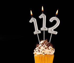 Birthday cupcake on black background - Number 112 shaped candles.