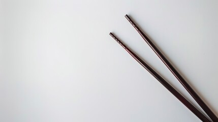 Naklejka premium Simple pair of chopsticks placed gracefully on clean white background. Elegant utensils for dining, essential in Asian cuisine traditions. Traditional tool for picking up food items like rice, vegetab