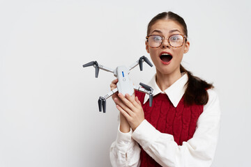 Drone, technology, excitement, girl holding drone, astonished expression, modern gadget, indoor setting, white background, casual attire, youthful energy