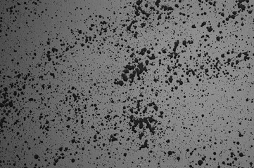 The photo shows a grey wall with splashes, streaks and blots of black paint