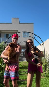 casal brinca com cachorros em area externa 