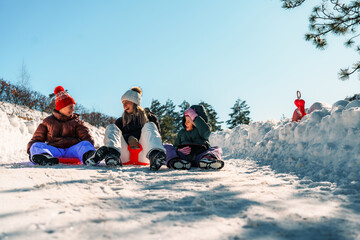 Mother and daughters laughing and enjoying quality time while sledding down a snowy hill on a bright winter day, embracing the joy of togetherness and adventure in the outdoors
