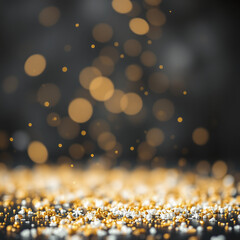 A shower of golden glitter and bokeh lights falling onto a surface covered in golden glitter, creating a festive and luxurious atmosphere against a dark background