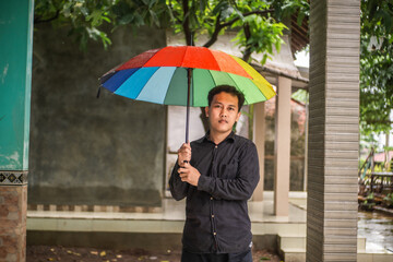 Man using rainbow multi-colored umbrella during drizzle