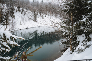 A scenic snowy river flowing gracefully through a serene landscape that is beautifully adorned with trees blanketed in thick, white snow, creating a picturesque winter wonderland