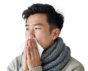 Young man wearing a warm knitted scarf holding a tissue to his face. Isolated on a transparent background, concept of cold and flu