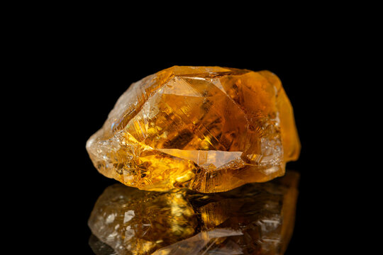 Closeup rough uncut citrine gemstone on dark background (selective focus)