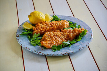 crispy fried fish fillets served on a blue plate with fresh lemon and parsley