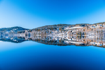 panorama of the lake in the sunny weather with blue sky above and the clear reflection in water during the winter time in Germany
