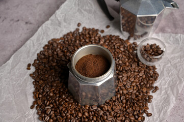 Ground coffee in a geyser coffee maker moka machine. Scattered fresh aromatic coffee beans around. Light background. Preparation to making coffee